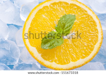 Composition of fresh orange fruit slices with ice cubes and mint herb leafs.