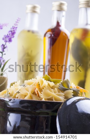 Raw food composition - yellow, green and orange colored farfelle, brown rotini and yellow rotelle pasta placed on a bright background.