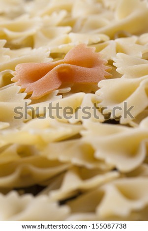 Raw food composition - yellow and orange farfalle pasta on a dark background.