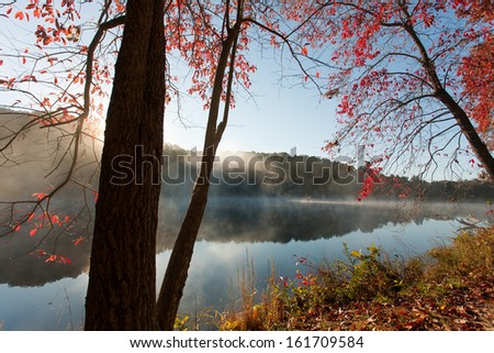 Colorful fall trees on the edge of a lake at sunrise.  Rose Lake, Hocking Hills State Park, OH, USA.