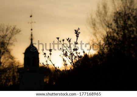 Trees & a church silhouetted by the setting sun.  Mission Church, Mackinac Island, MI, USA.