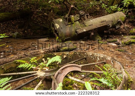 An old rusted steam engine laying in a creek, surrounded by parts.  Great Smoky Mountains National Park, TN, USA.