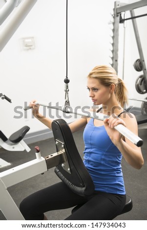 Confident young woman doing weight exercise in health club