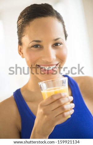 Young woman holding glass of orange juice at gym
