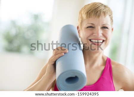 Woman holding rolled up exercise mat at gym