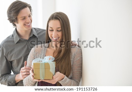 Happy young man giving birthday gift to woman at home