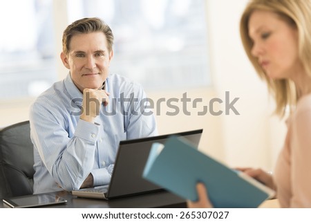 Portrait confident businessman with female colleague at desk in office