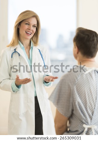 Happy female doctor discussing with male patient in hospital