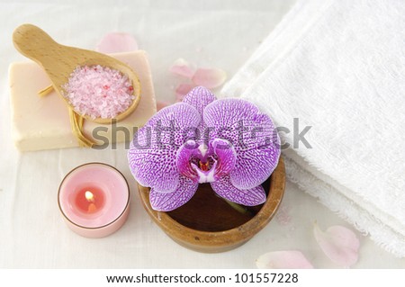 Spa products with orchid flowers and candle, soap, towel with salt in spoon
