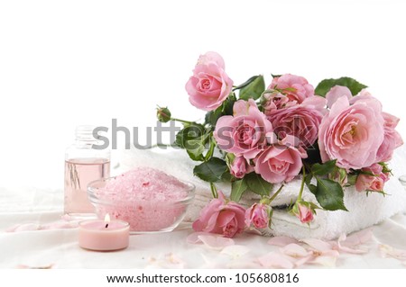 Spa setting with branch roses on towel and candle, salt in bowl, massage oil