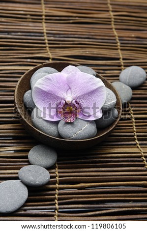 Row of stones with orchid with stones in bowl on mat
