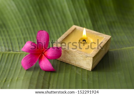 Red frangipani flower and handmade candle on banana leaf