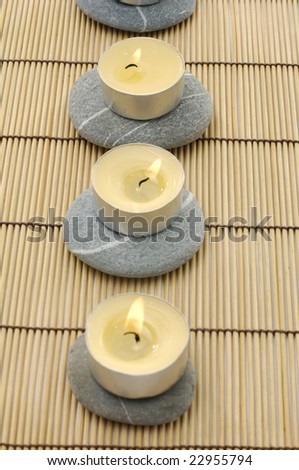 Zen stones and candle on a wooden bamboo set