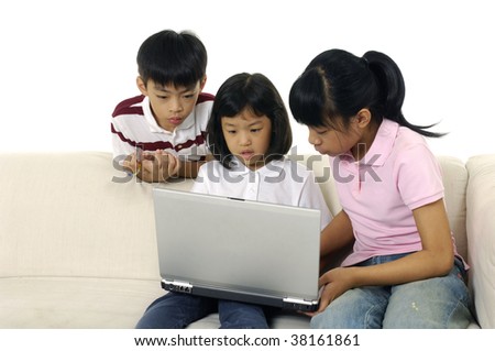 Young brother and sister sitting on couch at home, browsing internet on laptop computer