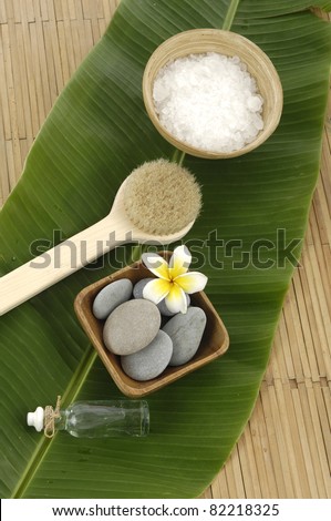 Bowl of Sea salt with and stones and massage oil with banana leaf on mat