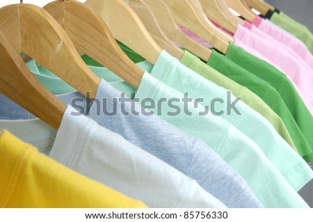 line of multi colored shirts on wooden hangers