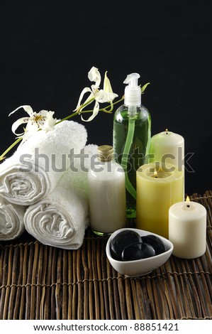 roller towel with massage oil .candle ,bowl of stones, orchid All on the bamboo mat.