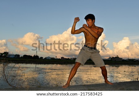 Full body very fit male model with muscles in exercise outdoors.