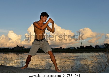 Full body very fit male model with muscles in exercise outdoors.