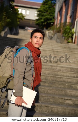 portrait of male college student holding book at campus