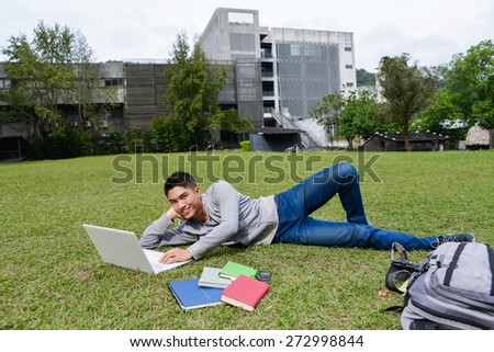 male college student lying on use laptop on a campus