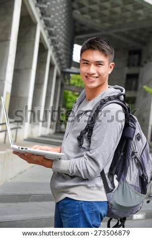 Asian student holding laptop in her hand at campus