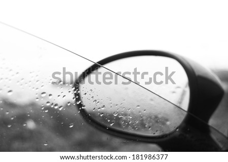 Drops of water on car window and rear view mirror (black and white photo)