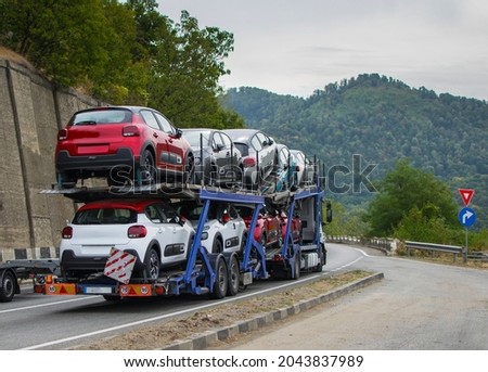 Car transporter transports new cars to the showroom. Cars arranged on two levels. Cars of different colors.No logo or brand. 商業照片 © 