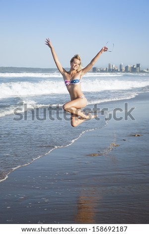 Young beautiful caucasian girl jumping on beach in american flag bikini