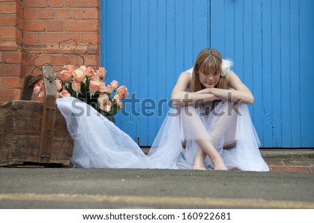 Young attractive caucasian woman sitting on sidewalk leaning her head on her knees