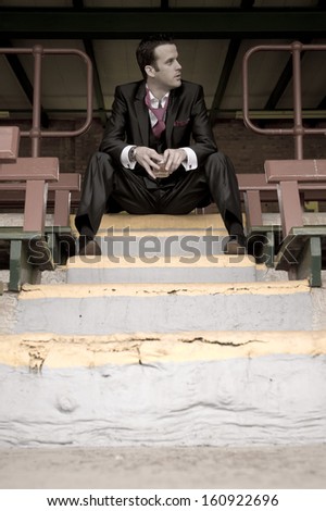 Young attractive man wearing a dress suit sitting on grand stand stairs