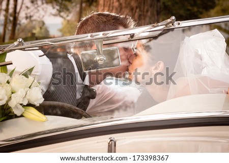 Young attractive caucasian bridal couple kissing in white vintage car