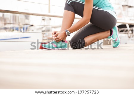 Young athletic runner tying shoe laces on wooden deck