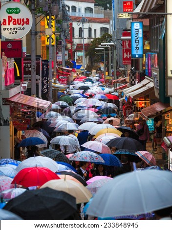 TOKYO - October 5 2014: People walk through Takeshita Dori near Harajuku train station with umbrella in a raining day on October 5 2014. Harajuku is considered a birthplace of Japan\'s fashion trends.