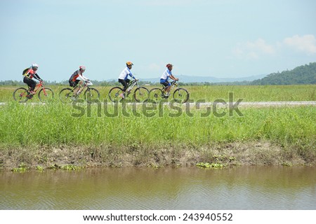 Kota Belud, Sabah Malaysia. October 22, 2014 : A group of cyclist cycling along gravel road near Kampung Sangkir paddy field in Kota Belud Sabah.