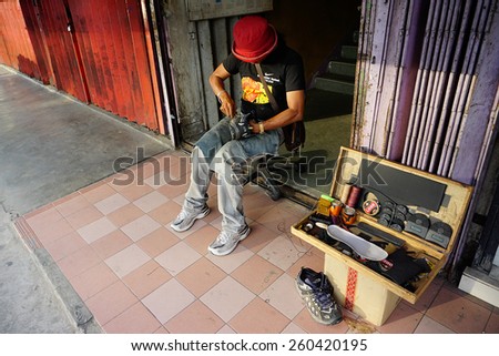 Kota Kinabalu Sabah Malaysia - February 8, 2015.Unidentified cobbler does his job at street of Kota Kinabalu.Most street cobbler in the city is dominated by immigrant from Southern Philipines.