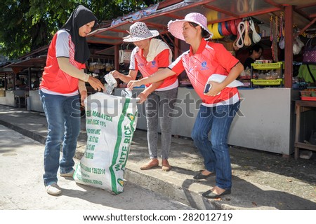 Kota Kinabalu, Sabah Malaysia - May 28, 2015.A Group of three woman volunteers picking up litter at street of Kota Kinabalu Sabah Malaysia to maintain cleanliness and to prevent dengue disease.