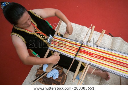Penampang Sabah Malaysia -31 May 2015 : A lady making traditional hand weaving cloth during the Pesta Kaamatan or Harvest Festival in Kota Kinabalu, Sabah.Image with shadow.