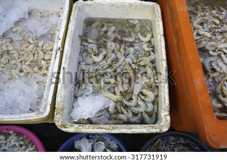 A selection of shrimp inside cooler box with ice at a fish market.