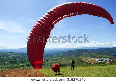 Ranau Sabah Malaysia - May 18, 2014:Unidentified person taking off with a paraglider at Sonsoluyon spot.This paragliding spot is popular with scenic view with Mount Kinabalu as an major attraction.