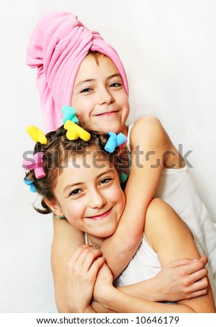 Beauty day of twin smiling sisters: one with curlers the other with a towel on her head. More available!