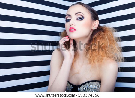 Graphic portrait of beautiful young woman with professional party make up false eyelashes on stripy background