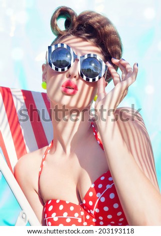 Colorful summer portrait of young attractive woman wearing bikini and sunglasses sitting by the swimming pool