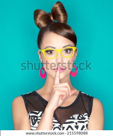 Young attractive fashionable woman with finger on lips, secret concept