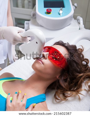 Woman getting face laser treatment in medical spa center, permanent hair removal concept