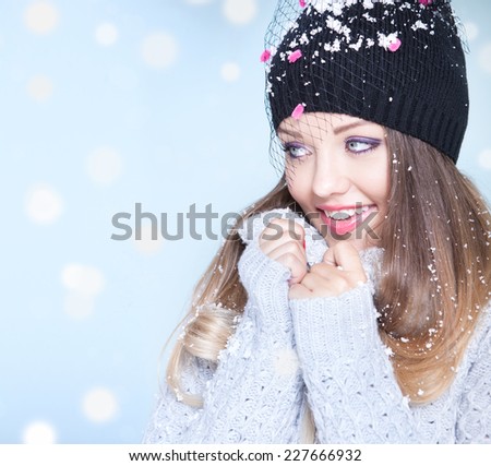 Winter face close up of young attractive woman wearing hat covered with snow flakes. Christmas concept.