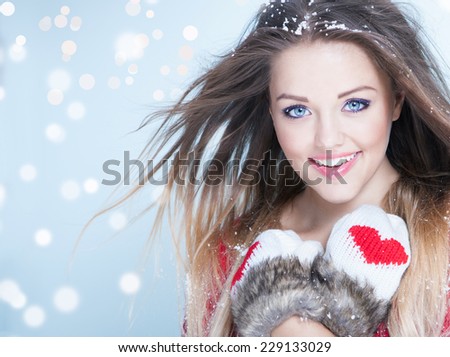 Beautiful happy young woman wearing winter gloves covered with snow flakes. Christmas portrait concept.
