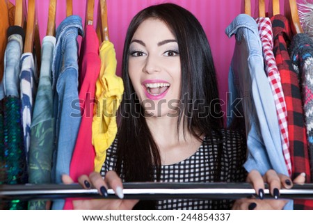 Young attractive laughing woman searching for clothing in a closet
