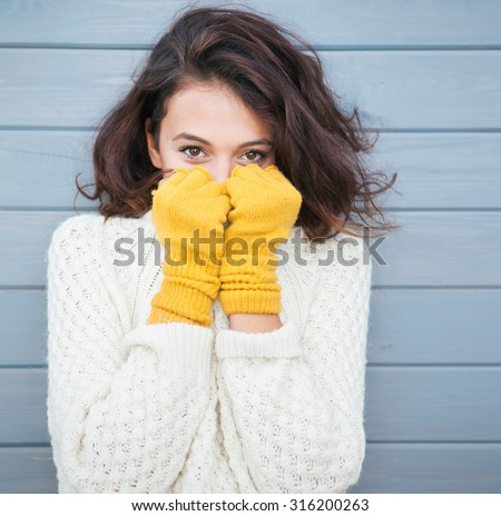 Beautiful natural young smiling brunette woman wearing knitted sweater and gloves. Fall and winter fashion concept.