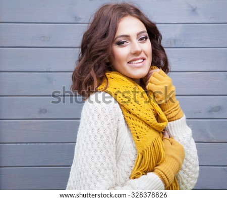 Beautiful natural young smiling brunette woman wearing knitted sweater gloves and scarf. Fall and winter fashion concept.